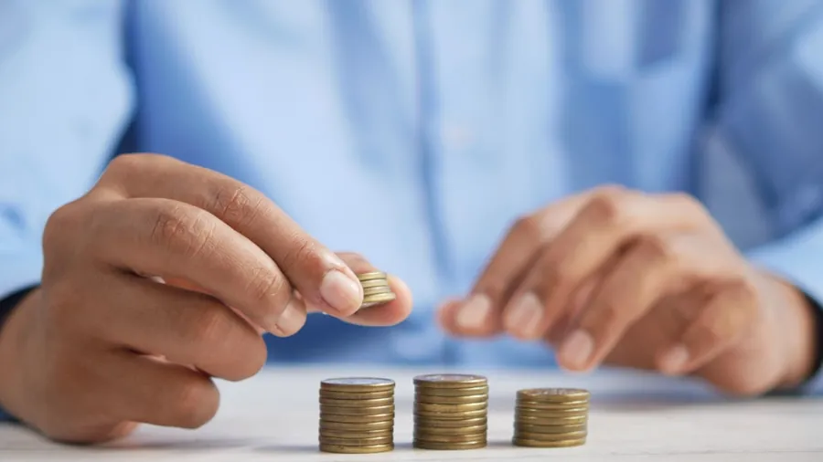 Hands counting and stacking coins on a table, working through a budget